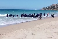 Migrants scatter as a rubber dinghy lands on the beach at Cadiz, southern Spain, Aug. 9. 