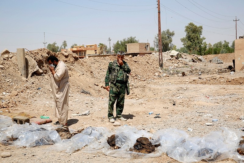 Militia fighters and civilians cover their faces as they stand near bodies recently dug up from a mass grave outside the town of Sulaiman Pek, Iraq Sept. 5, 2014. (Reuters Photo)