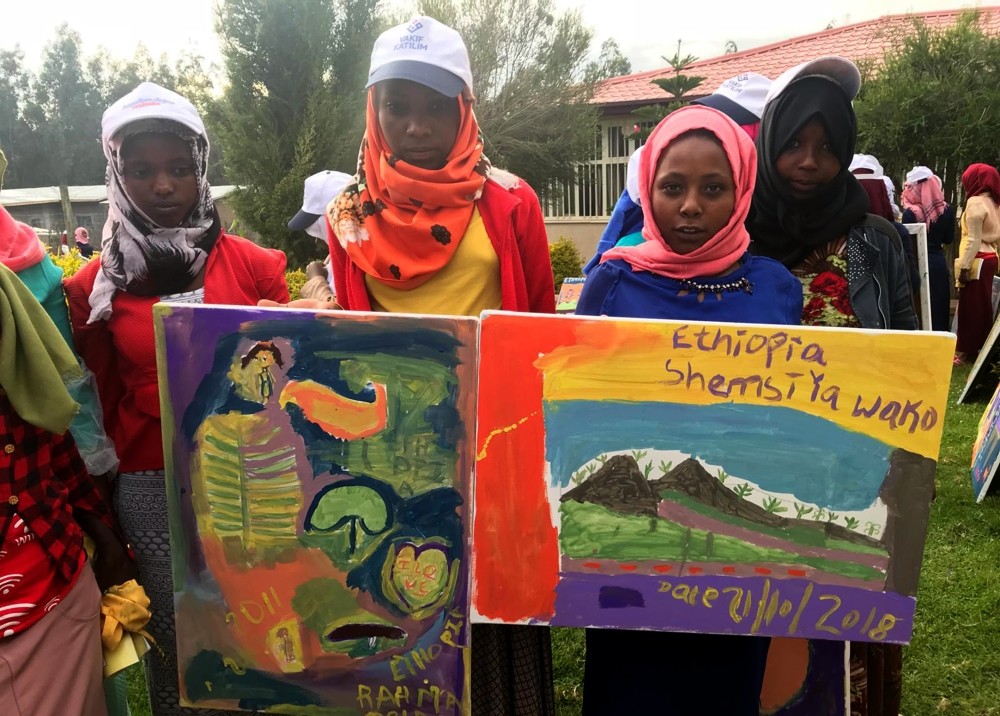 Ethiophian children show the paintings they did.