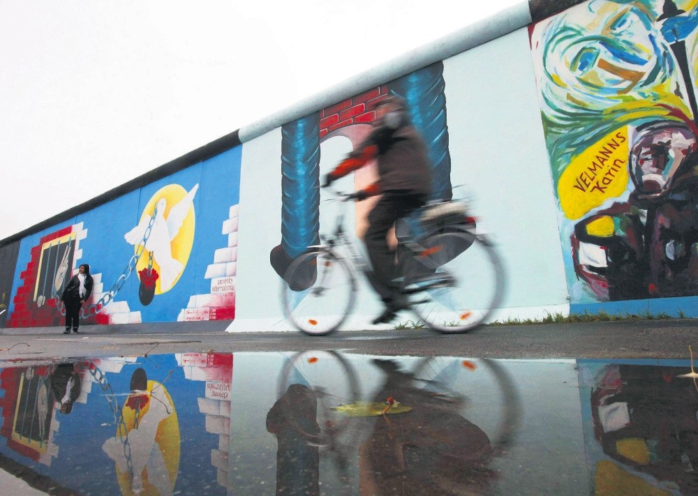 A cyclist passes a segment of the East Side Gallery in Berlin.