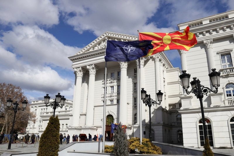 Macedonian, right, and NATO flag wave in front of the government building during a ceremony in Skopje, Tuesday, Feb. 12, 2019. (AP Photo)