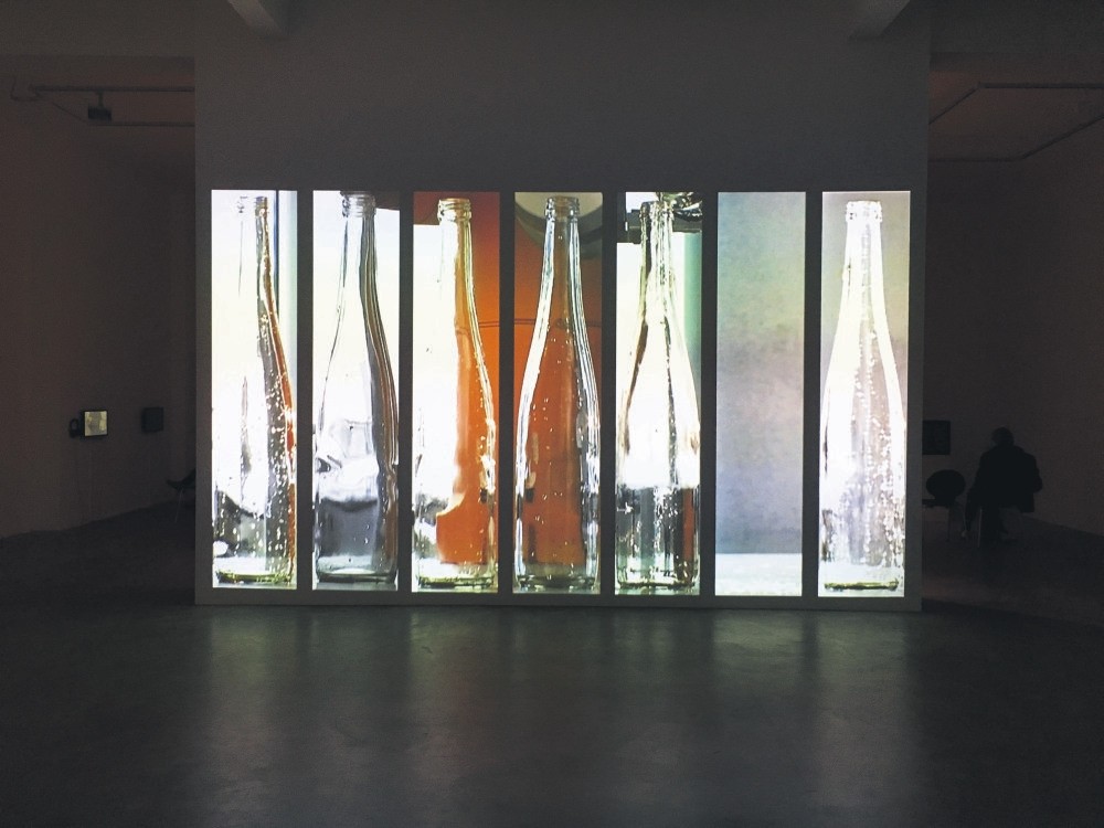 The showcase starts with a huge, almost small cinema scale video projection of u201cRe-Pouringu201d (2010) that shows a robotic hand and six glass water bottles recorded vertically.