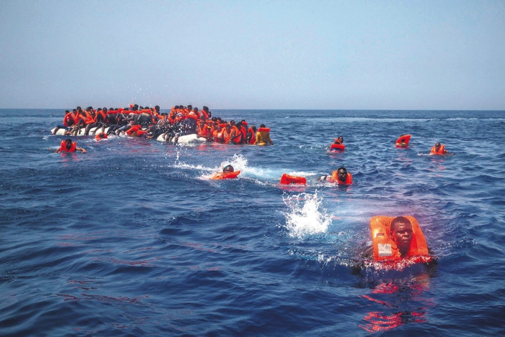 African migrants try to reach a Spanish NGO Proactiva Open Arms rescue ship after falling from a punctured rubber boat in the Mediterranean Sea, about 12 miles north of Sabratha, Libya, July 23.