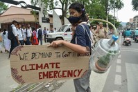 A youth connected to a jug with a plant inside holds a placard at a protest calling for the Indian government to declare a climate emergency in Guwahati on Nov. 8, 2019. (AFP)
