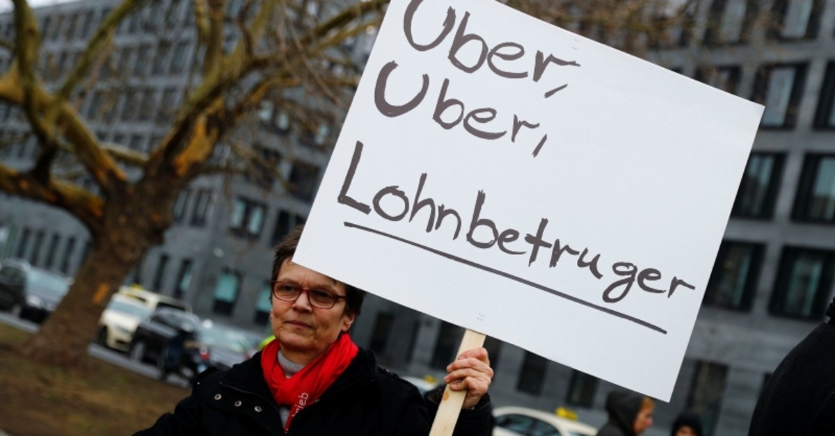 A licensed taxi driver protests against a planned change of the passenger transport law in front of the Federal Department of Transportation in Berlin, Germany, February 21, 2019. The placard reads: ,Uber, Uber, wage cheater.,  (Reuters Photo)