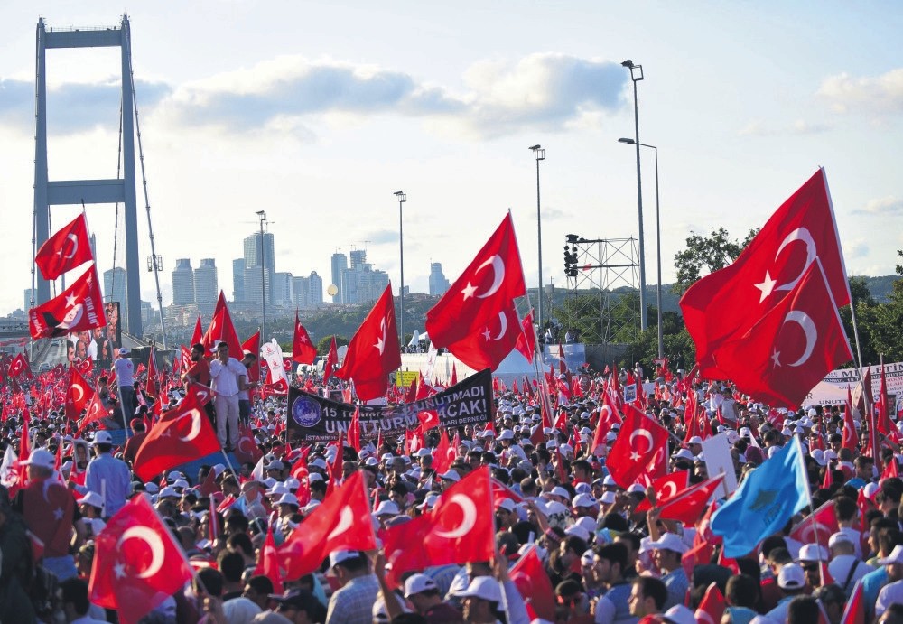 People wave Turkish flags as they stand near the July 15 Martyrs Bridge to commemorate the first anniversary of the bloody coup attempt, Istanbul, July 15.
