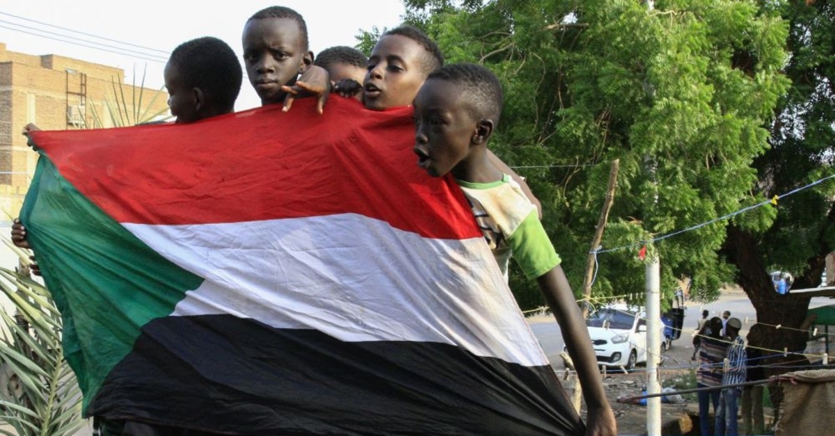 Young Sudanese boys carry a national flag as they celebrate the historic transitional constitution, Bahri, Aug. 18, 2019.