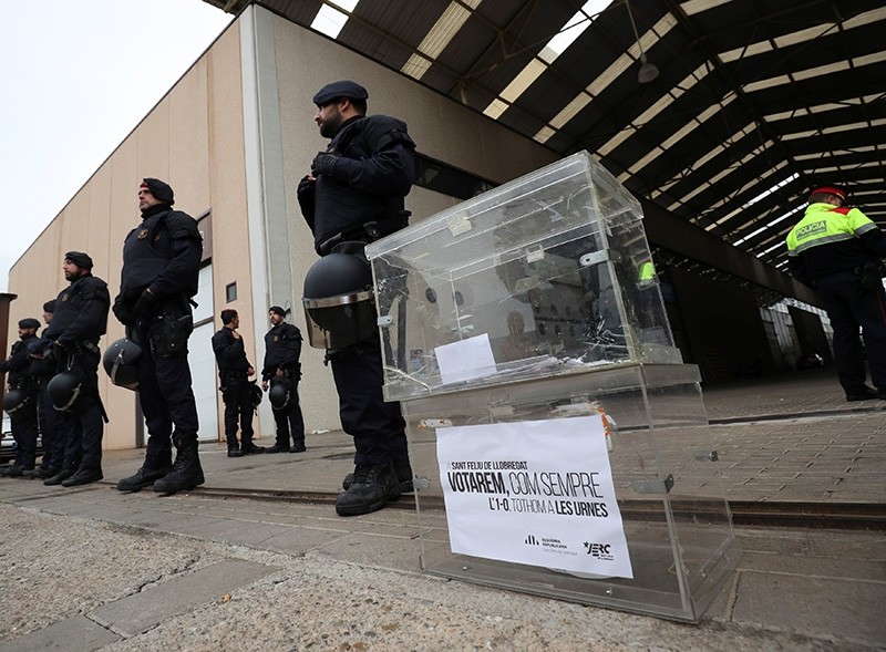 A ballot box, placed by demonstrators, is seen next to Catalan regional police members, who stand guard outside a printing facility, during a raid in search of ballot papers in Sant Feliu de Llobregat, Spain, Sept. 15, 2017. (Reuters Photo)