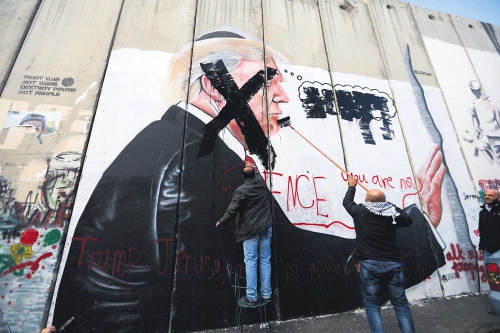Palestinians paint an X over the face of a picture of President Trump that was painted on the Israeli separation wall in Bethlehem, West Bank, during protests against Trump's decision to recognise Jerusalem as the capital of Israel. Dec. 17.