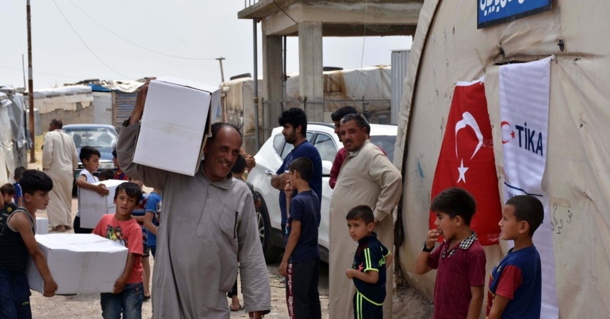 An Iraqi man carries a food package delivered by Tu0130KA at a distribution point, May 27, 2019.