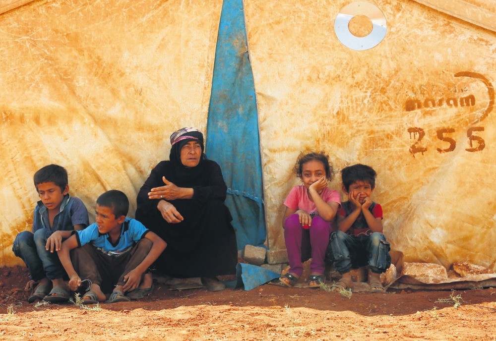 Displaced Syrians sit by a tent at a camp in Kafr Lusin, in Syria's Idlib, near the border with Turkey, Sept. 9.