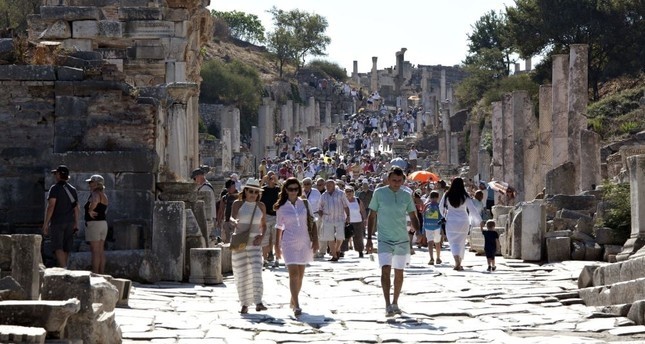 Tourists walking on u0130zmiru2019s Curetes Street, which is one of the main streets of Ephesus, connecting the Magnesia gate to the Koresos gate.