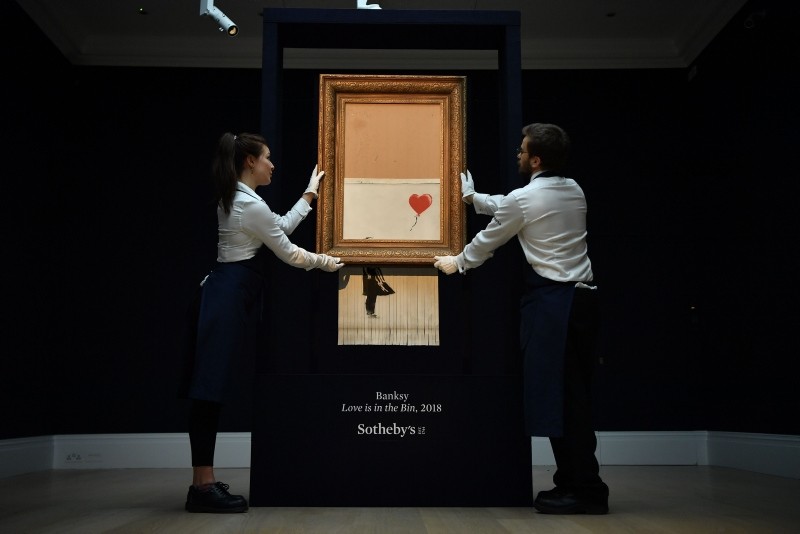 Sotheby's employees pose with the newly completed work by artist Banksy entitled ,Love is in the Bin, at Sotheby's auction house in London on October 12, 2018. (AFP Photo)