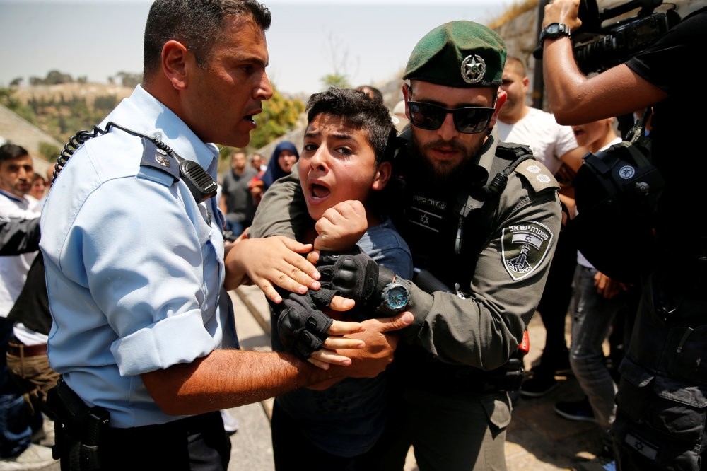 A Palestinian youth is detained by an Israeli border police officer during scuffles that erupted after Palestinians held prayers just outside Jerusalem's Old City