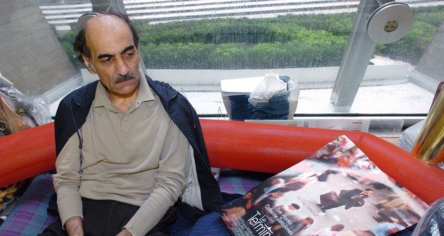 المعارض الإيراني مهران كريمي ناصر الذي عاش 18 عاماً داخل مطار شارل ديغول الفرنسي بجانب الملصق الدعائي للفيلم الهوليوودي ذا ترمينال الذي صدر عام 2004 وهو مستوحى عن قصته AFP