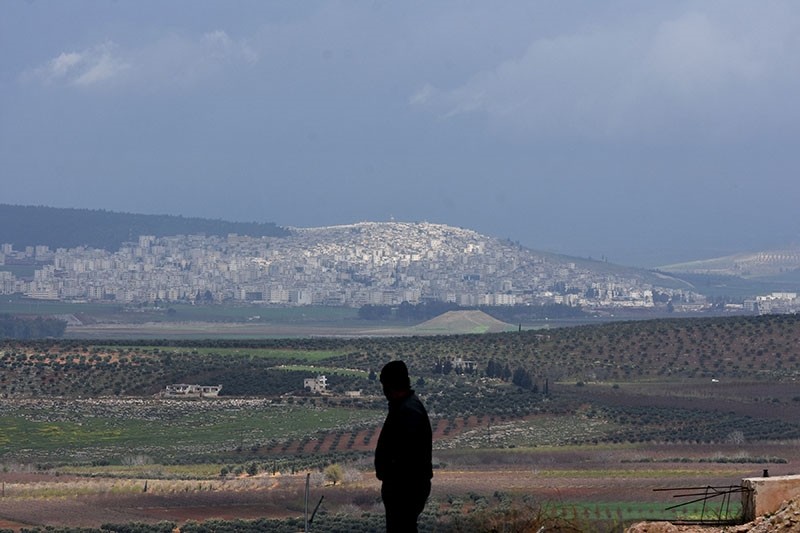 A civilian fleeing the city of Afrin (background) in northern Syria stands at the mountainous road of al-Ahlam as he heads towards the check point in az-Ziyarah, in the regime-controlled part of the Aleppo province, on March 15, 2018. (AFP Photo)
