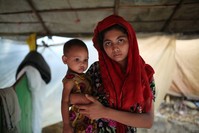A Rohingya woman holds her child and stands for a photograph at a makeshift camp near the Kutupalong refugee camp in Cox's Bazar, Bangladesh, Oct. 3.