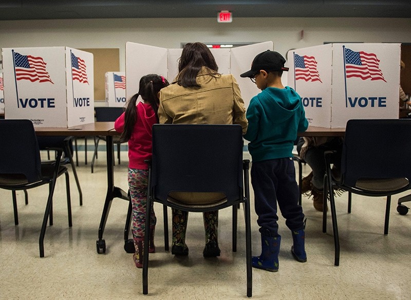 A woman and her children vote at a polling station during the mid-term elections at the Fairfax County bus garage in Lorton, Virginia on Nov. 6, 2018. (AFP Photo)