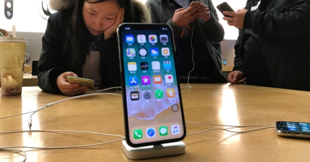 In this Nov. 6, 2017, file photo, shoppers check out the iPhone X at an Apple store in Beijing, China. (AP Photo)