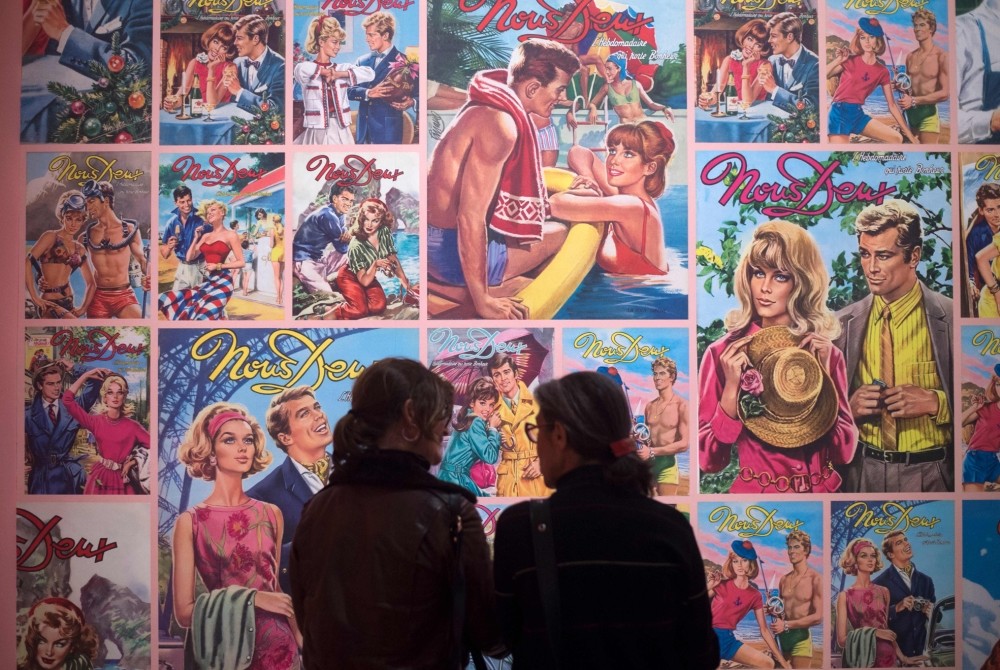 Women stand in front of covers of the photo novel ,Nous Deux, during a press preview of the exhibition ,Roman-Photo.,
