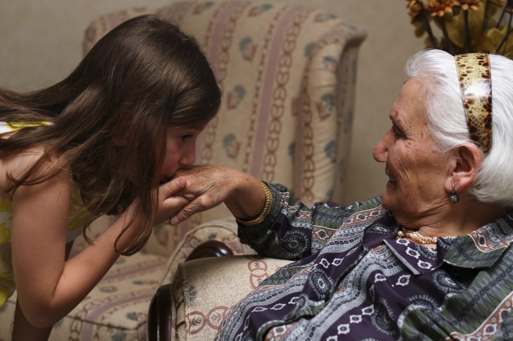A little girl kissing the hand of her grandmother which is a custom during the religious holidays in Turkey.