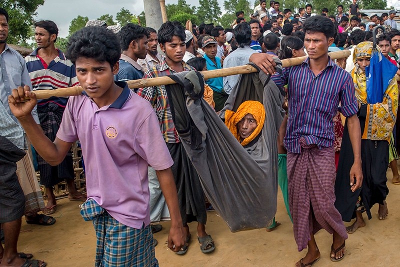 Rohingya Muslim men, who crossed over from Myanmar into Bangladesh, carry their mother in a cloth tied to bamboo stick at Kutupalong refugee camp, Bangladesh, Monday, Oct. 23, 2017 (AP Photo)