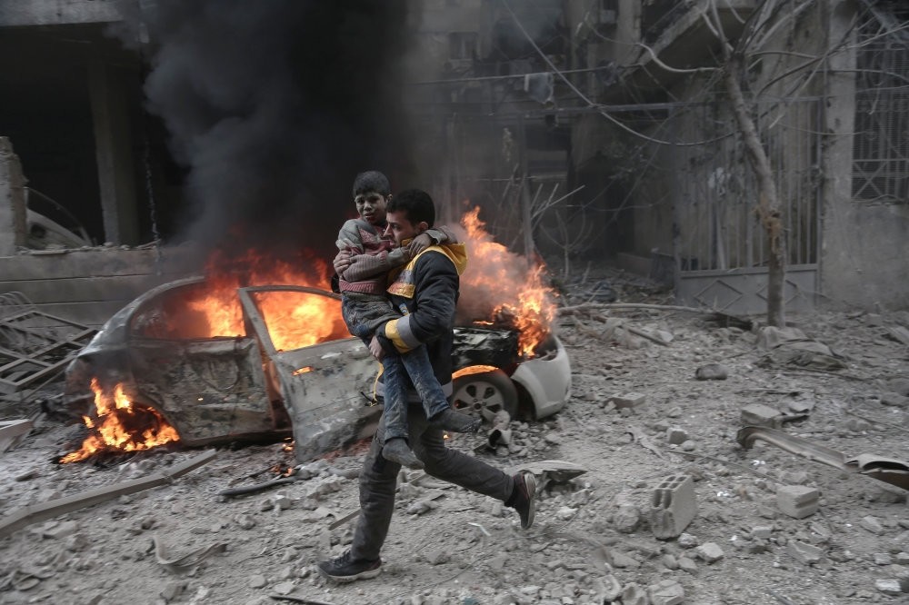 A Syrian paramedic carries an injured child following a reported bombardment by the Syrian regime in opposition-held Hamouria, eastern Ghouta, Jan. 6, 2018.