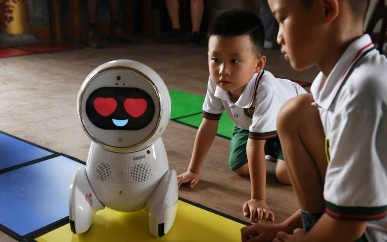 Children watch a Keeko robot make its way on a path they made from square mats at the Yiswind Institute of Multicultural Education in Beijing.
