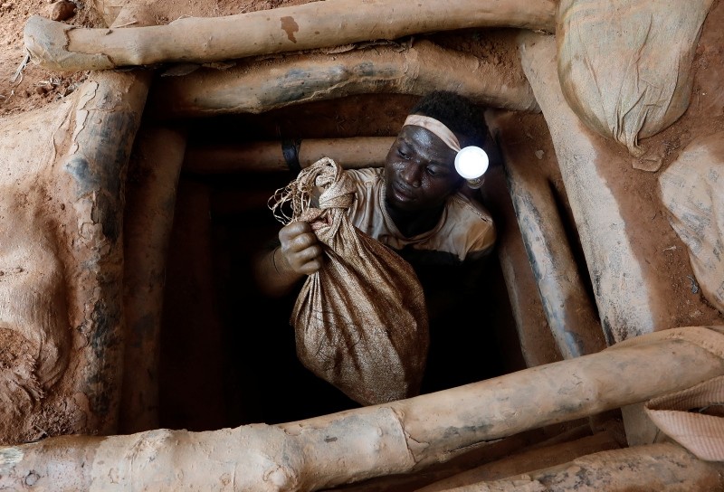An artisanal miner climbs out of a gold mine with a bag of rocks broken off from inside the mining pit at the unlicensed mining site of Nsuaem Top in Ghana, November 24, 2018.
