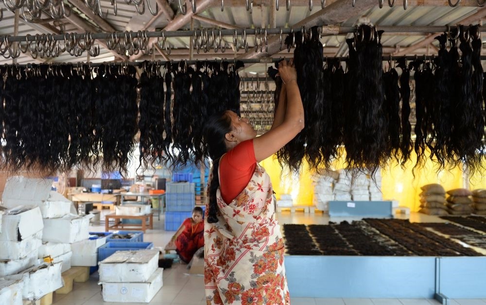 An Indian worker hangs human hair to dry after being washed at Raj Hair International's processing center in Alinjivakkam on the outskirts of Chennai.