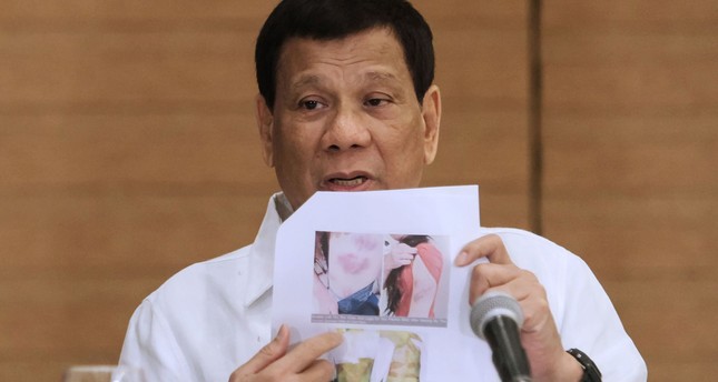 Philippine President Rodrigo Duterte shows a photo of a Filipina worker in Kuwait, of whom he said she had been roasted like a pig, during a press conference in Davao City, in the southern island of Mindanao on February 9, 2018. (AFP Photo)