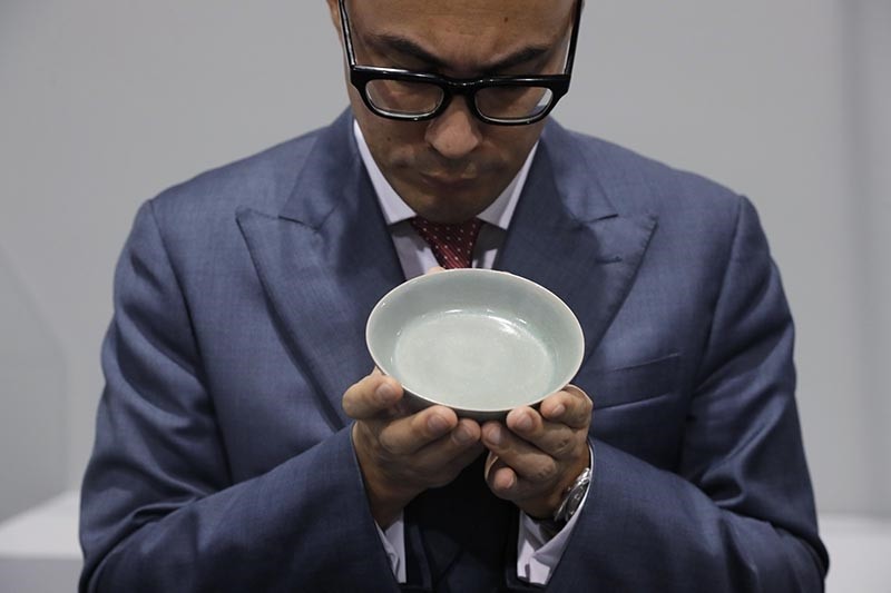 Nicolas Chow, a staff member from Sotheby's, presents the extremely rare Ru Guanyao brush washer from China's Northern Song Dynasty at the Sotheby's Hong Kong (AP Photo)
