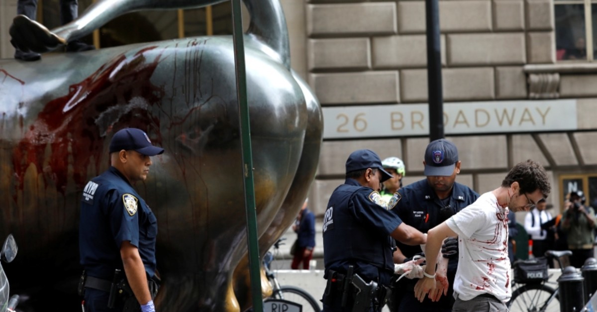 A climate change activist covered in fake blood is detained by police at the Wall Street Bull in Lower Manhattan during Extinction Rebellion protests in New York City, New York, U.S., October 7, 2019. (Reuters Photo)
