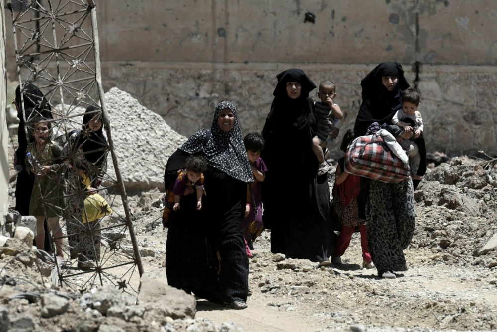 Displaced Iraqi women walk towards Iraq forces as they flee their homes in Mosul's western Al-Shifa district on June 15.