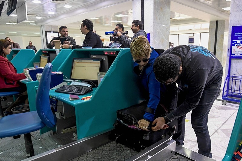 A Tunisian couple bound for London pack away their electronics in their luggage as they check-in for a flight at Tunis-Carthage International Airport on March 25, 2017. (AFP Photo)