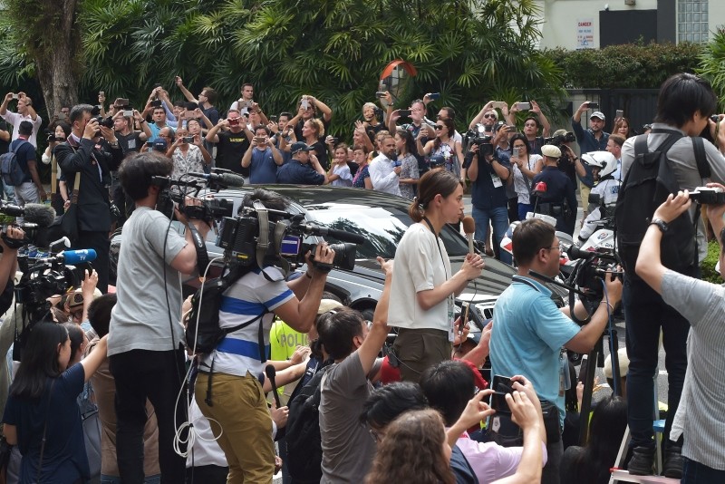 Journalists and onlookers watch the motorcade carrying North Koran leader Kim Jong Un (not pictured) arriving at the St. Regis hotel ahead of the US-North Korea summit in Singapore on June 10, 2018.  (AFP Photo)