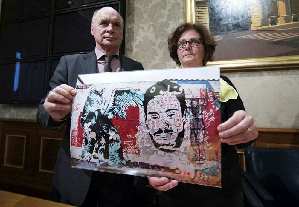 The parents of Giulio Regeni, an Italian graduate student tortured to death in Egypt, shows a pictures of a murales depicting their son. (ANSA via AP)