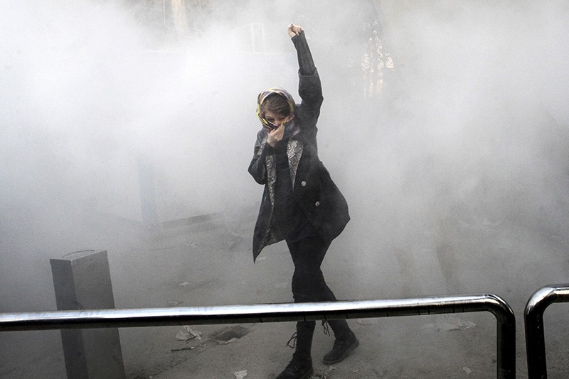 In this Dec. 30, 2017 photo, a university student attends a protest inside Tehran University while a smoke grenade is thrown by Iranian police, in Tehran, Iran. (AP Photo)