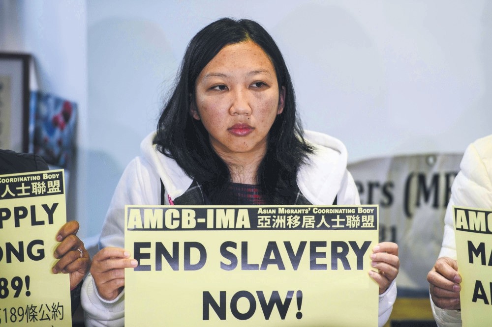 Erwiana Sulistyaningsih, a former domestic helper from Indonesia, holds a sign that reads ,End Slavery Now, during a press conference in Hong Kong.