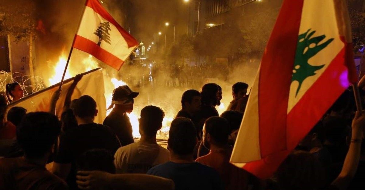 Anti-government protesters wave Lebanese flags in front of a barricade set aflame on a road leading to the parliament building, Beirut, Nov. 13, 2019. (AP Photo)