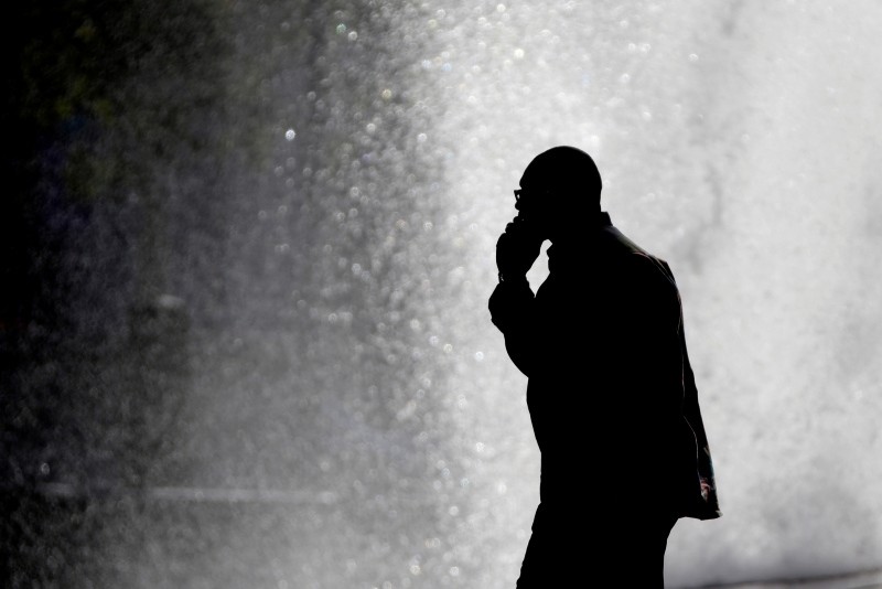 In this Thursday, Oct. 11, 2012 file photo, a pedestrian talking on a cellphone is silhouetted in front of a fountain in Philadelphia. (AP Photo)
