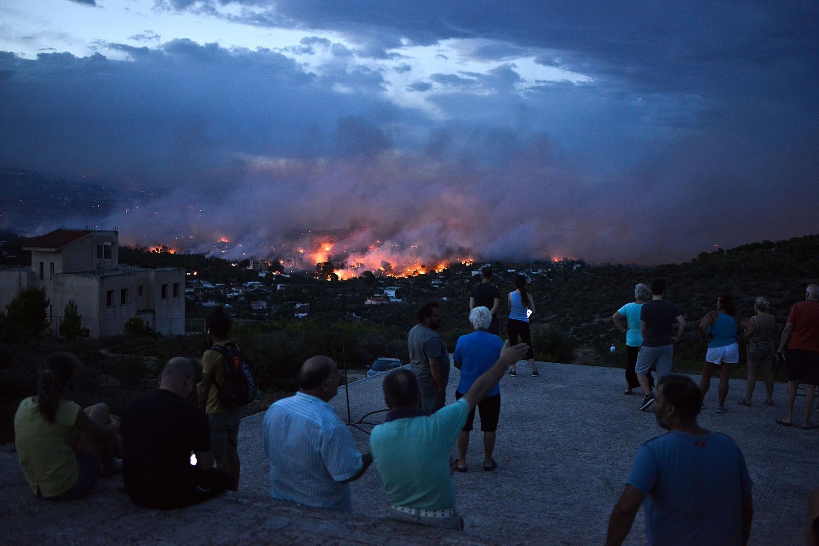 People watch a wildfire in the town of Rafina, near Athens, on July 23, 2018. 