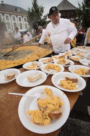 A member of the World Brotherhood of the Huge Omelet attends the making of a 6500 egg omelet within a 4 metre diameter frying pan on August 15, 2017 in Malmedy. (AFP Photo)
