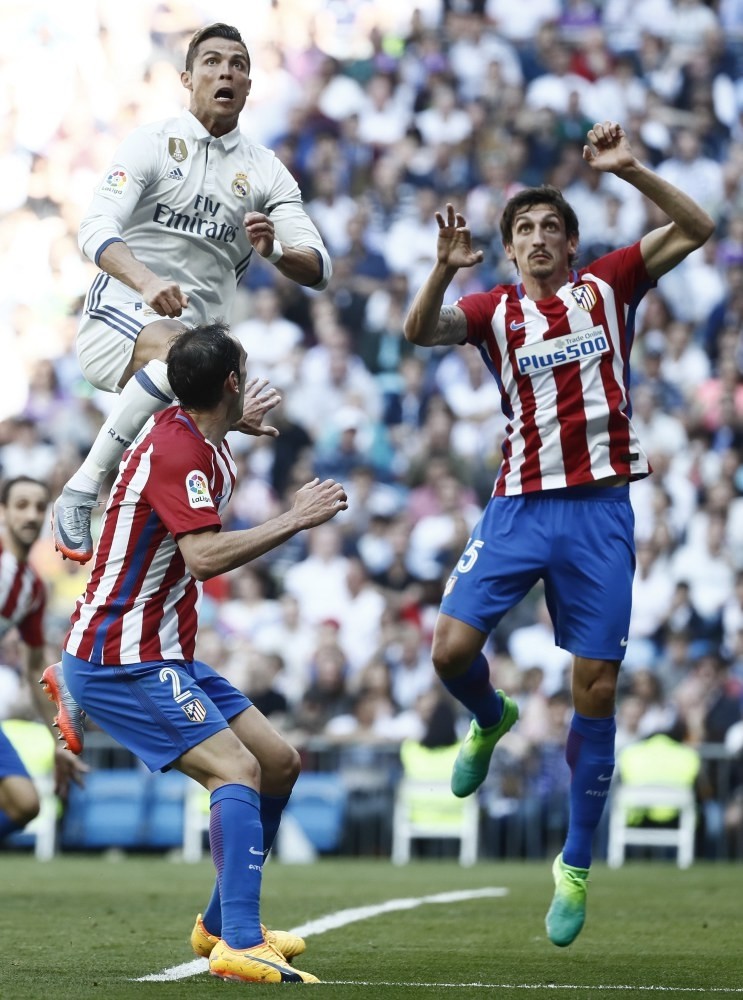 Real Madridu2019s Portuguese striker Cristiano Ronaldo (L) tries to score next to Uruguayan defender Diego Godin (C) of Atletico Madrid during the Primera Division match at Santiago Bernabeu stadium in Madrid on Apr. 8.