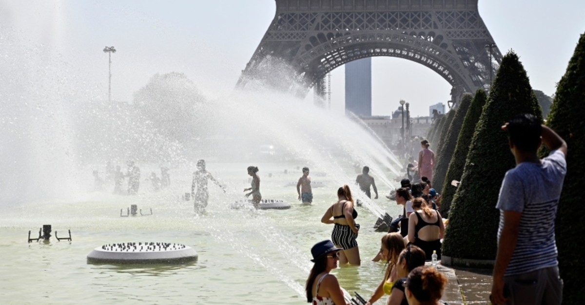 People cool off and sunbathe at the Trocadero Fountains in Paris, on July 25, 2019 as a new heatwave hits the French capital. (AA Photo)