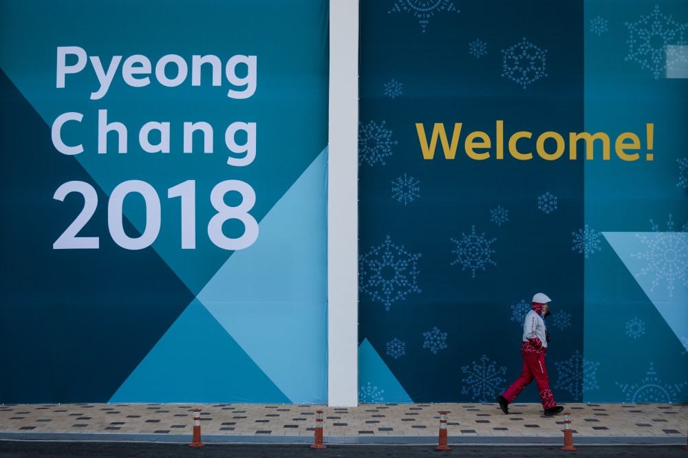 A volunteer walk past a large banner at the Gangneung Olympic Park prior to the 2018 Winter Olympics, Gangneung, South Korea, Feb. 5. AP