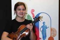 u0130lke Iu015fu0131 Tuncer poses in front of a poster for Iu015f Sanat's Shining Stars program.