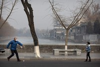 A man and girl wear face masks as they play badminton near the closed Forbidden City in Beijing, Jan. 27, 2020. (AP Photo)