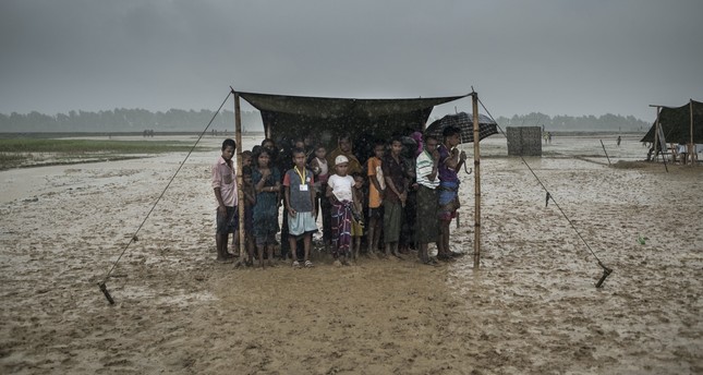 Rohingya Muslim refugees take shelter from the rain during a food distribution, Nayapara refugee camp, Ukhia, Bangladesh, Oct. 6, 2017.