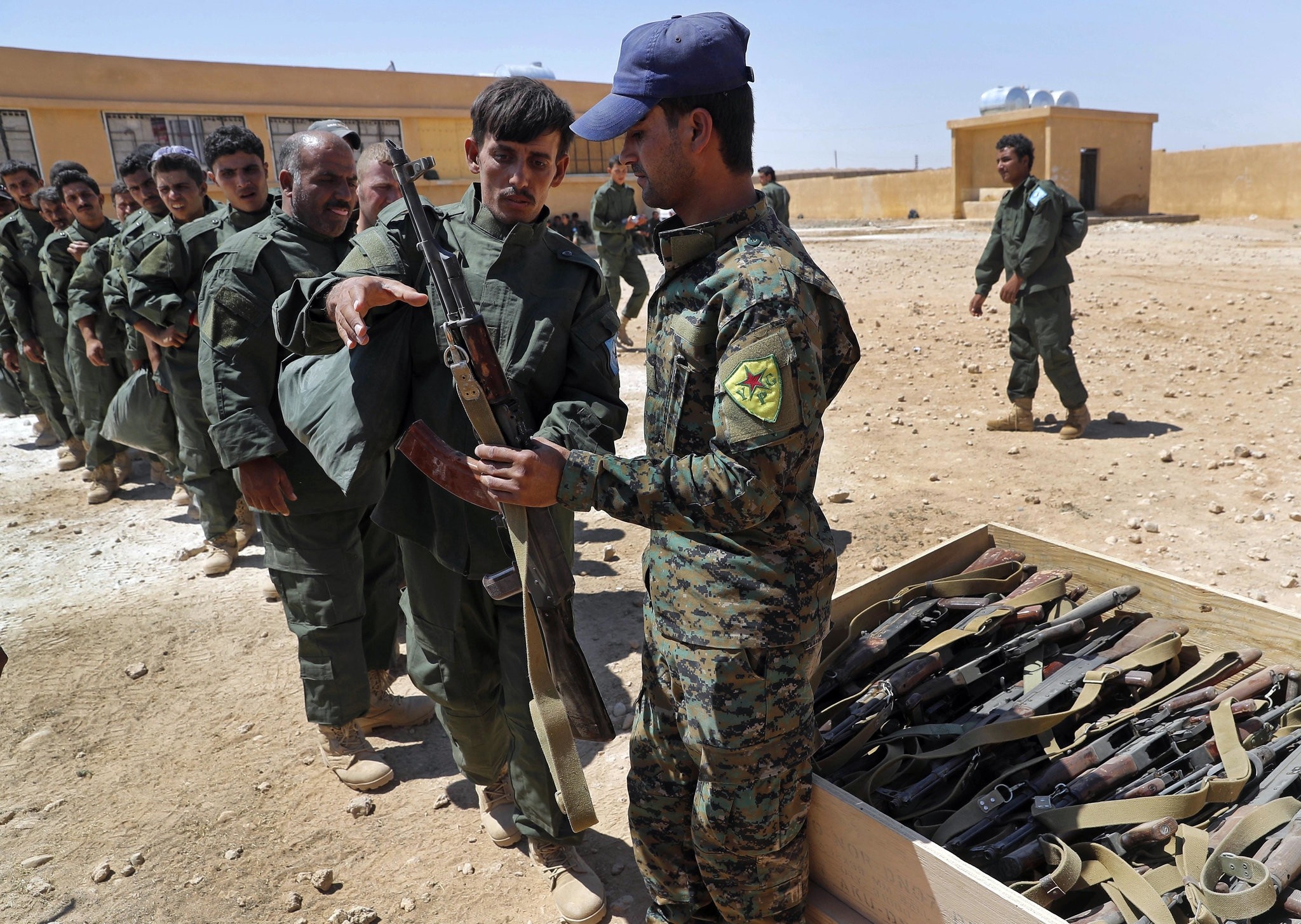 SDF forces receive weapons during their graduation ceremony, at Ain Issa desert base, in Raqqa province, northeast Syria, Thursday, July 20, 2017. (AP Photo)